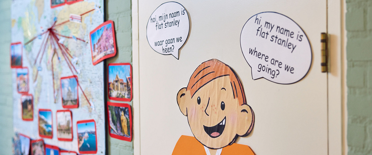 Voorbeeld van tweetalig onderwijs (TPO) op IKC De Eglantier: het personage Flat Stanley verwelkomt leerlingen in zowel het Nederlands als het Engels. De wereldkaart op de achtergrond illustreert het thematisch onderwijs en de open blik naar de wereld.